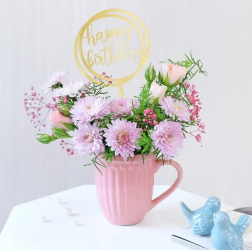 Charming Pink Floral Birthday Arrangement featuring a mix of pink blooms, greenery, and decorative accents, perfect for celebrating birthdays.