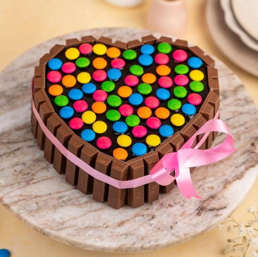 Heart-shaped KitKat Gems Cake decorated with chocolate bars and colorful candy gems, ideal for celebrations and special occasions.