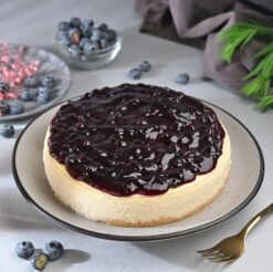 Blueberry Dripping Cheesecake with smooth, creamy filling and luscious blueberry sauce drizzle on top, offering a rich and indulgent dessert.