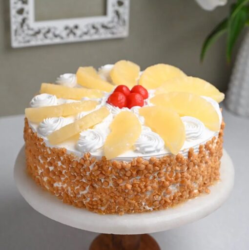 Tropical Vanilla Fruit Cake adorned with a variety of tropical fruits like pineapple, mango, and kiwi, on a soft vanilla base.