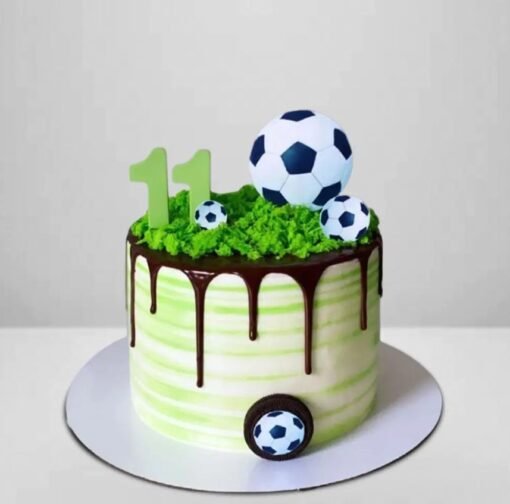 Round soccer-themed cake with edible soccer ball decorations and green grass frosting.